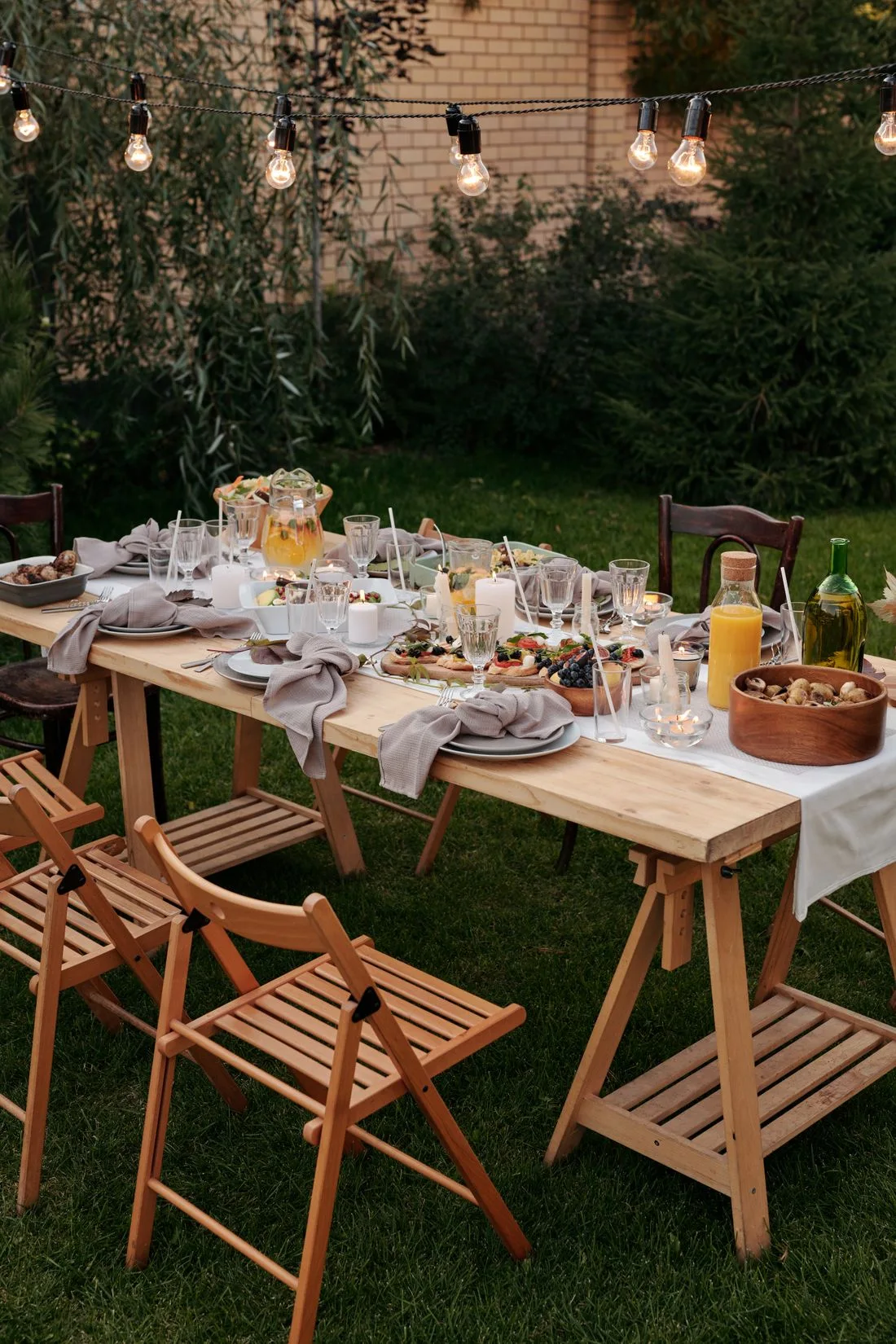Outdoor dining table with food beneath string lights