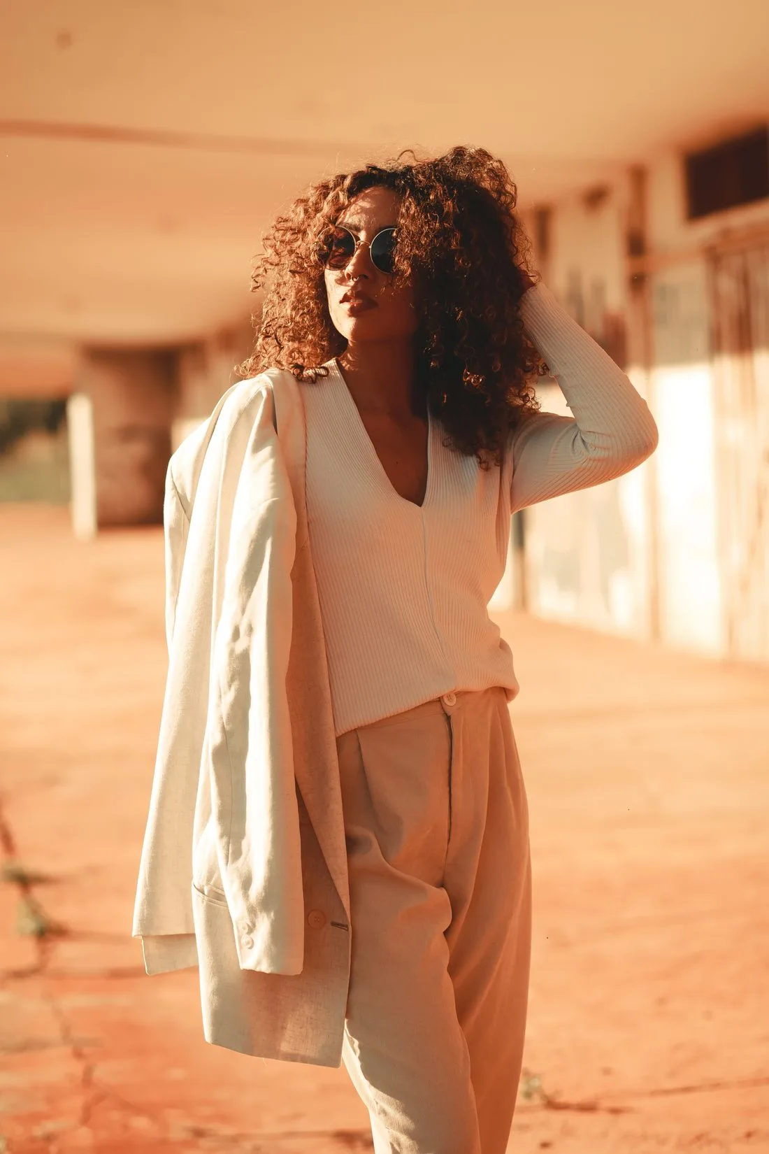 Woman wearing beige trousers and holding a jacket outdoors