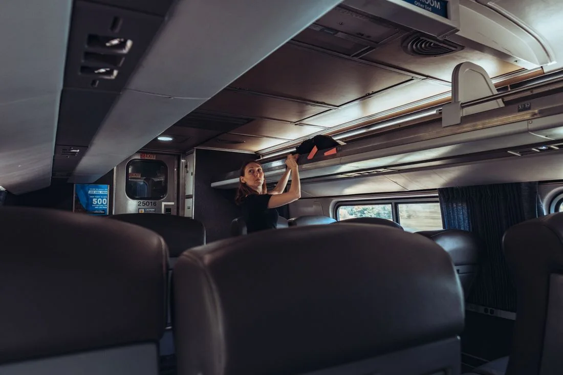 Traveler placing luggage in a train overhead compartment