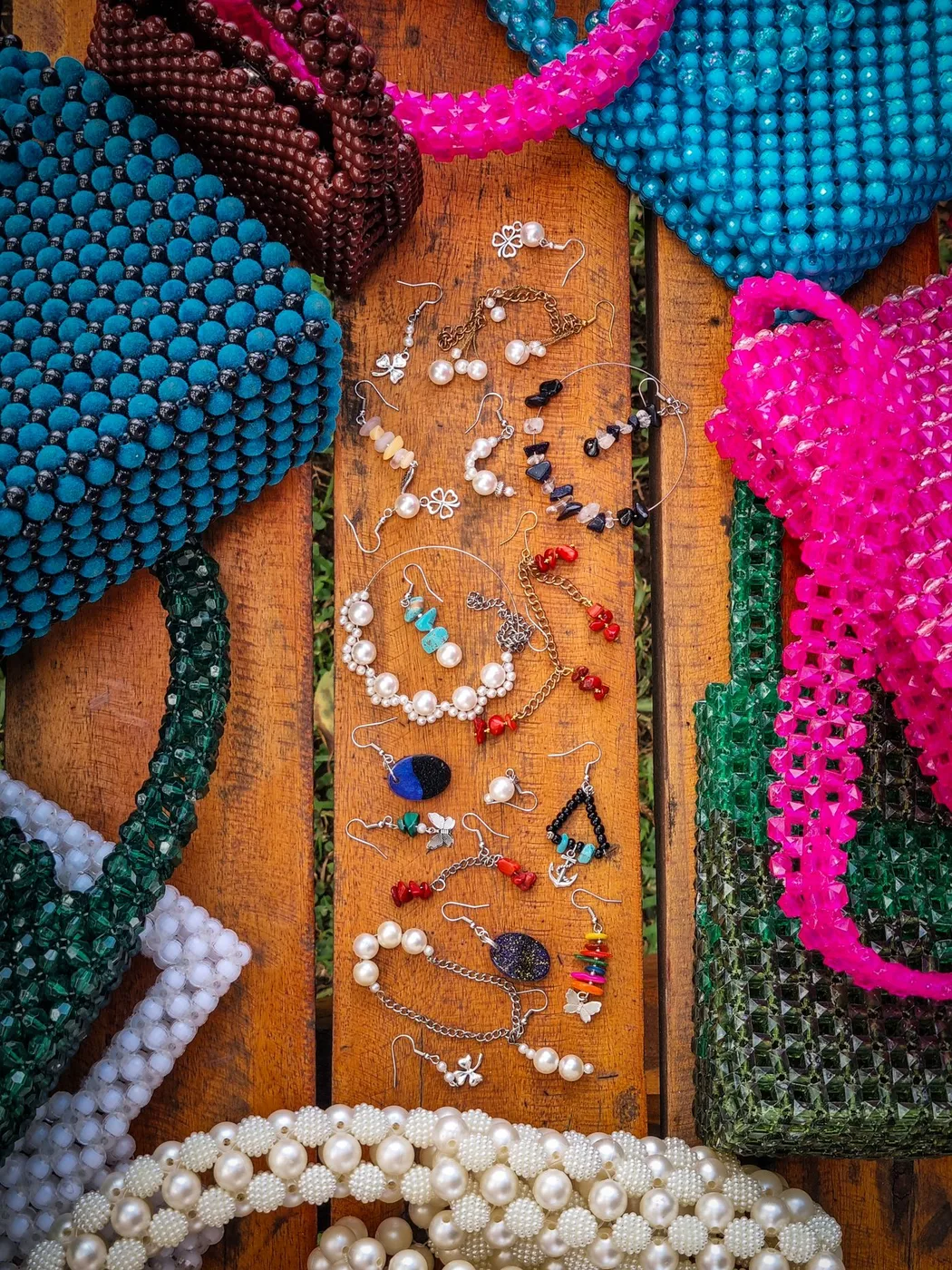 Colorful beaded handbags and jewelry displayed on wood