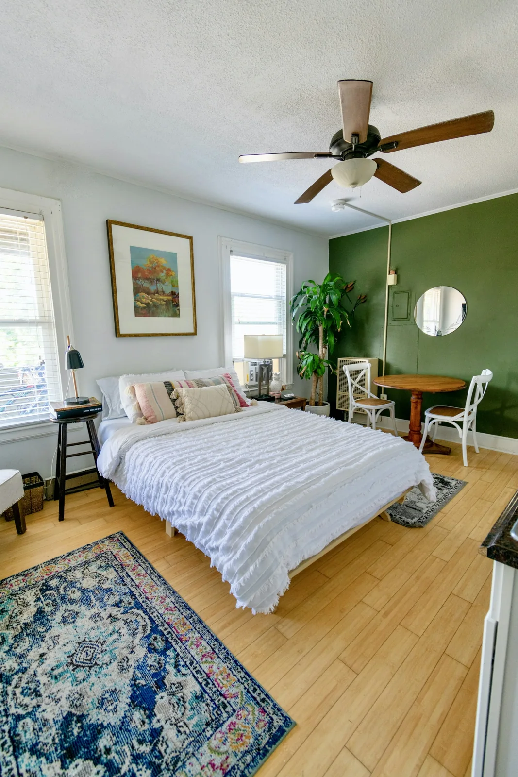 White bed linen in a sunlit bedroom with a green accent wall