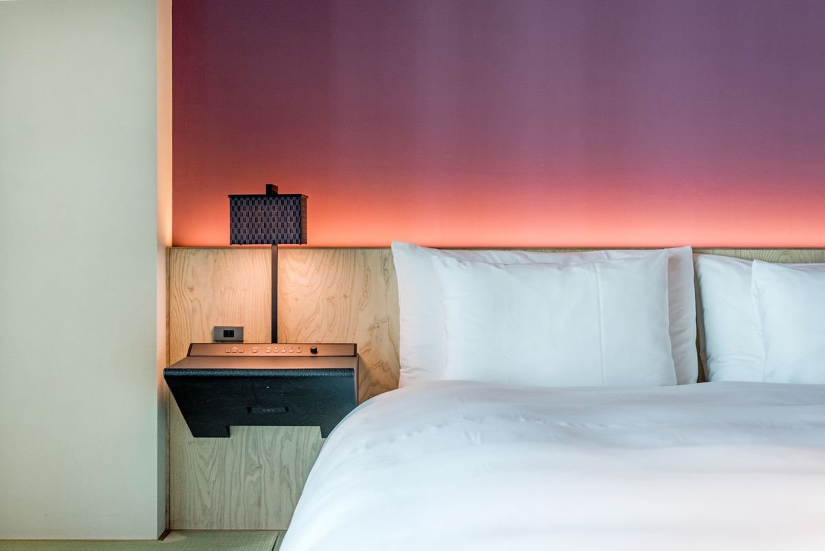 Illustrative hotel bedroom with white pillows and warm bedside lighting