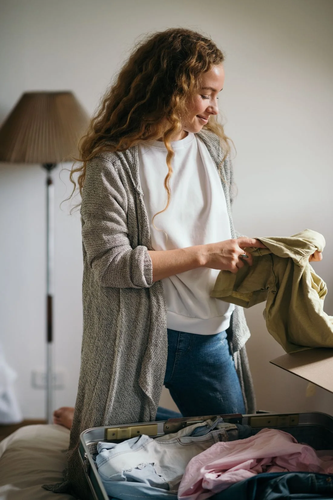 A woman holding a garment in a bedroom