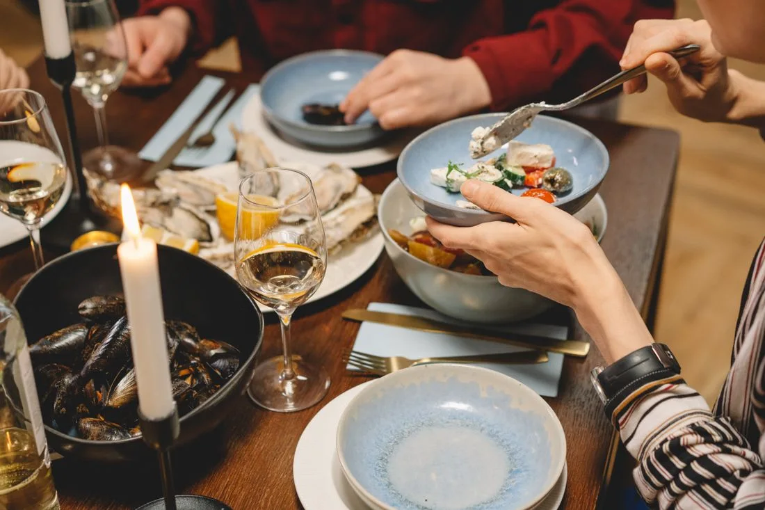 People sharing seafood and wine at a candlelit wooden table