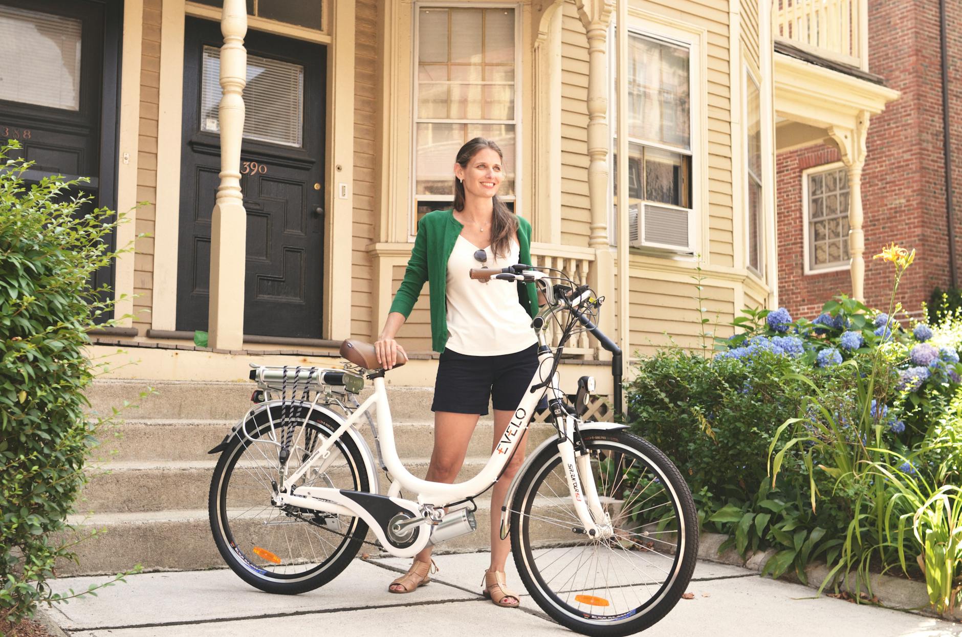 a woman in a green cardigan holding an electric bike