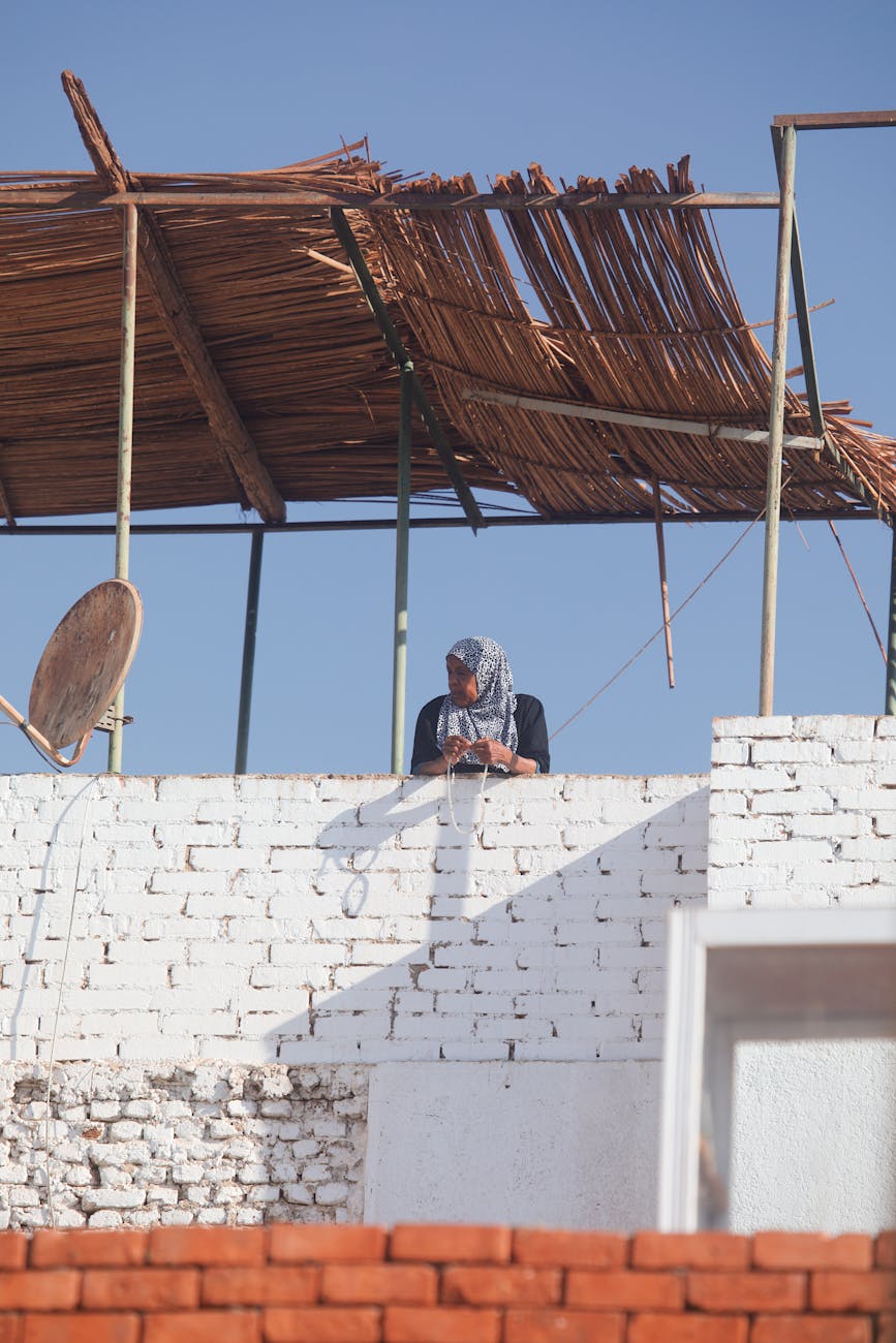 a woman is sitting on top of a brick wall
