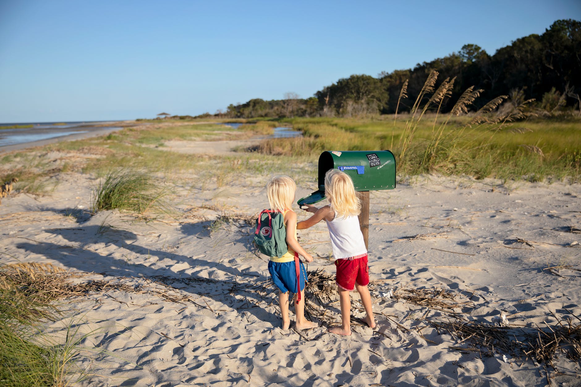 two children standing beside green mailbox