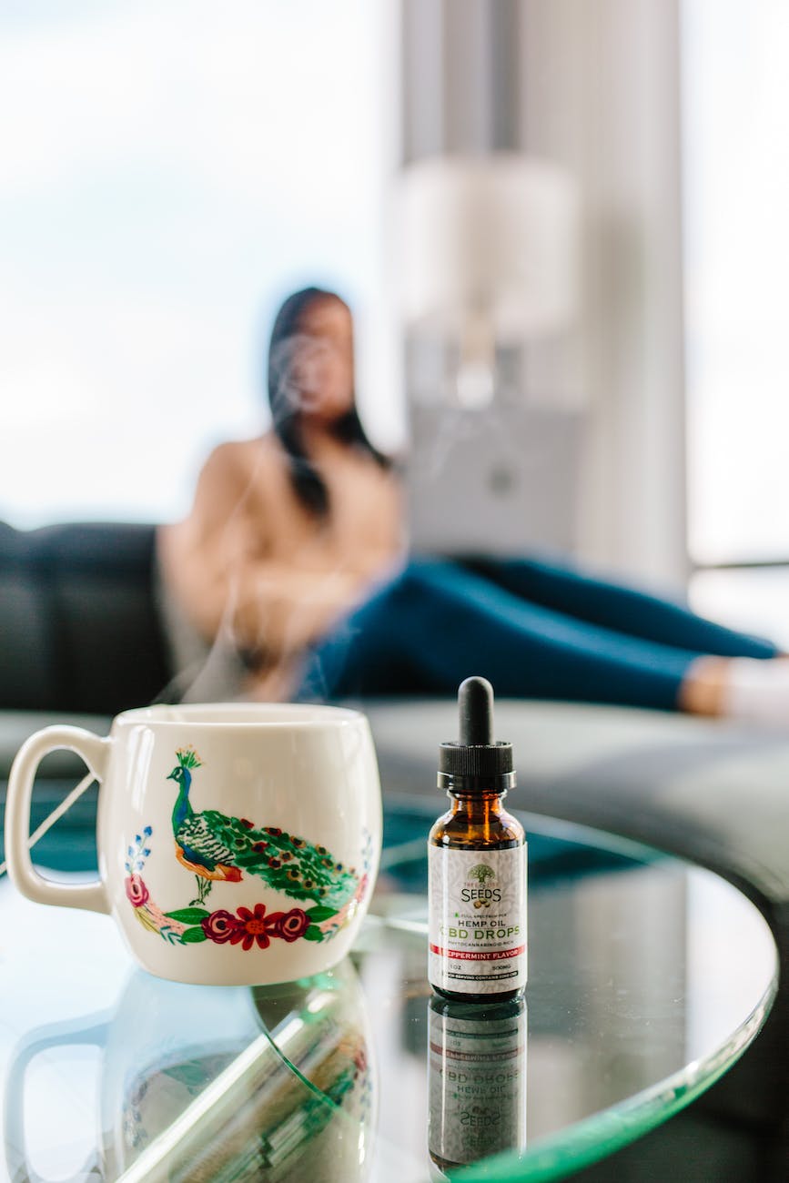 bottle of cbd drops next to cup with hot drink