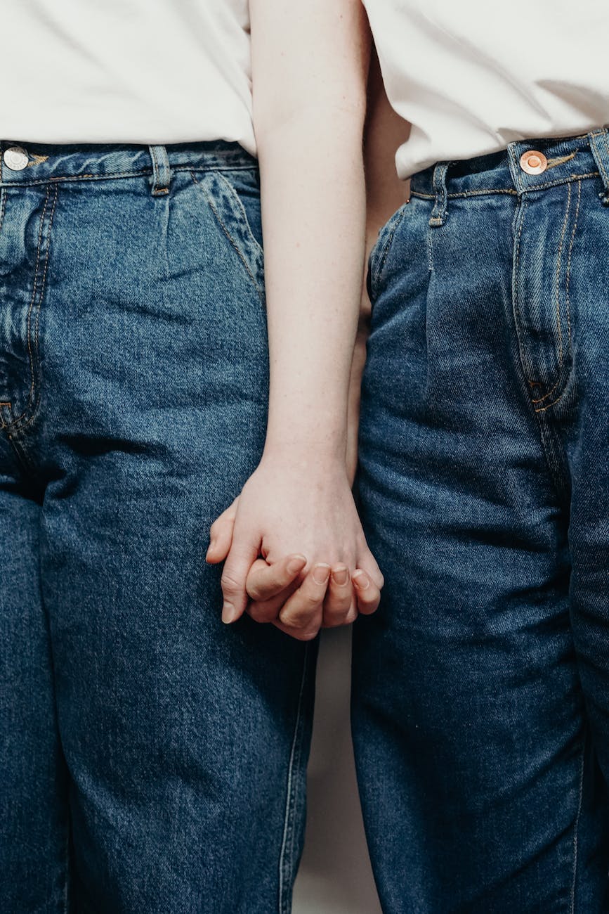 persons wearing denim jeans while holding hands