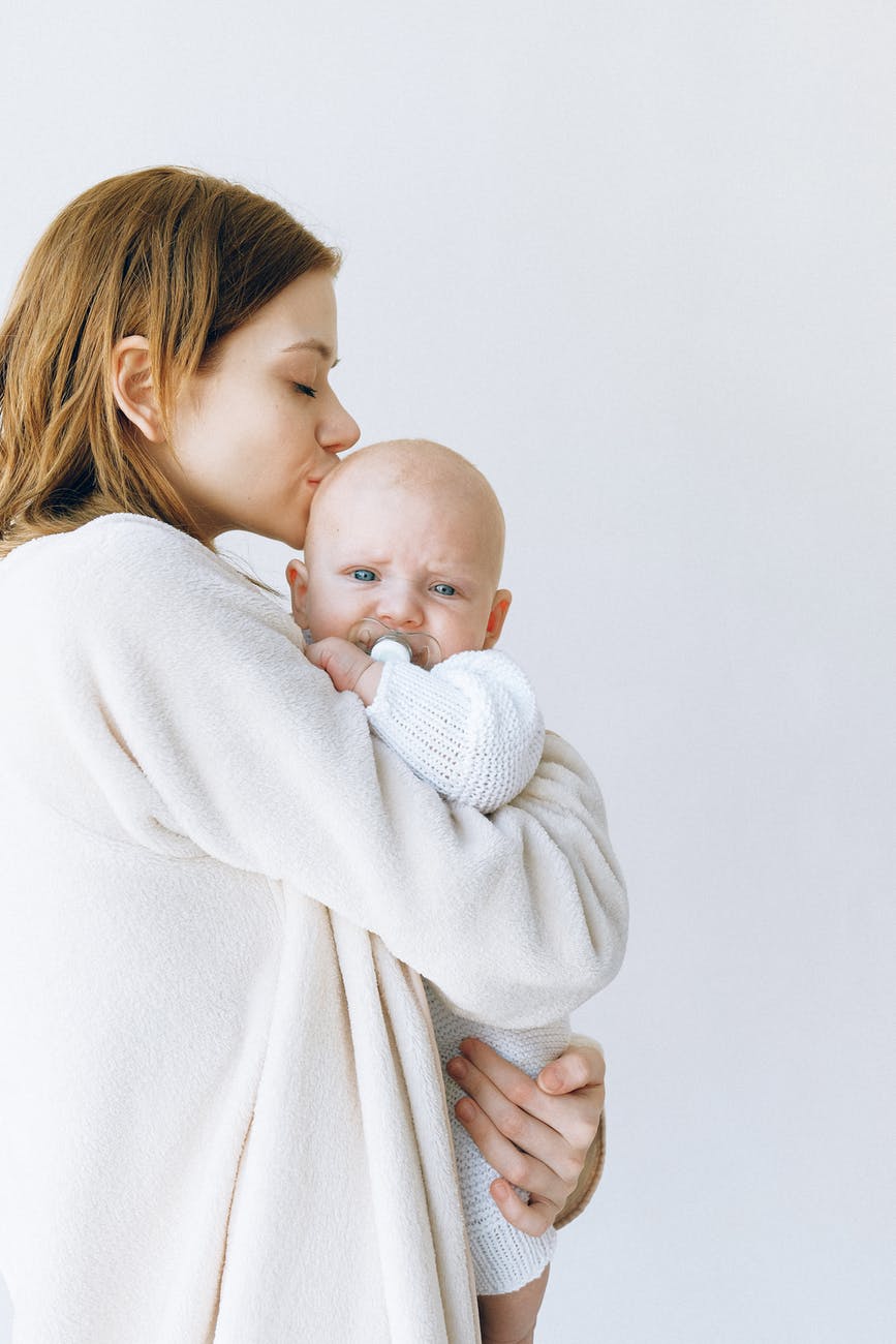 woman in white robe carrying baby