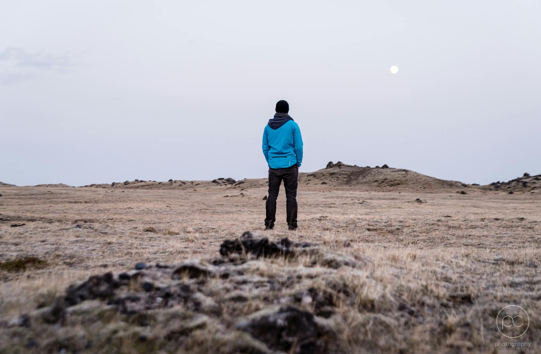 man in blue hoodie standing on brown grass