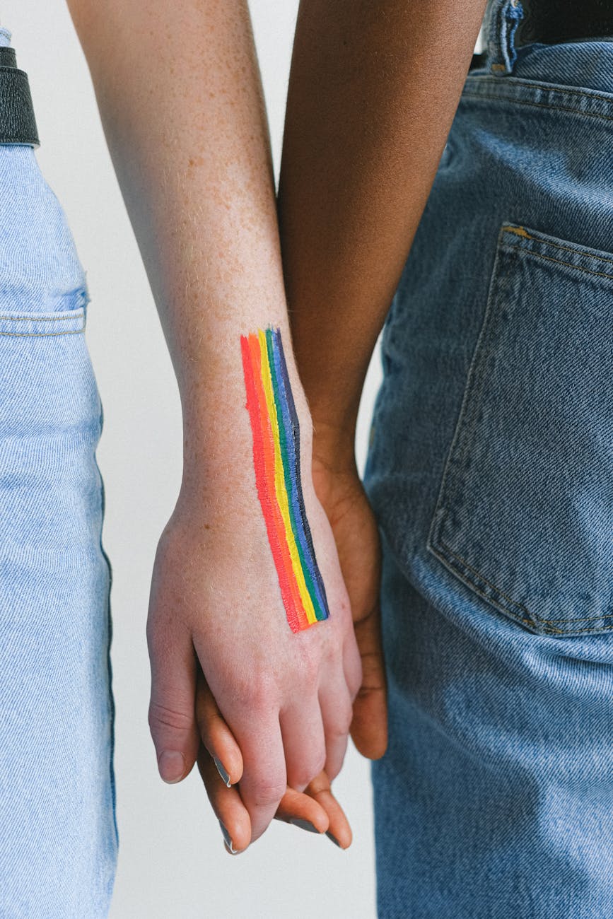 people with gay pride body paint holding hands