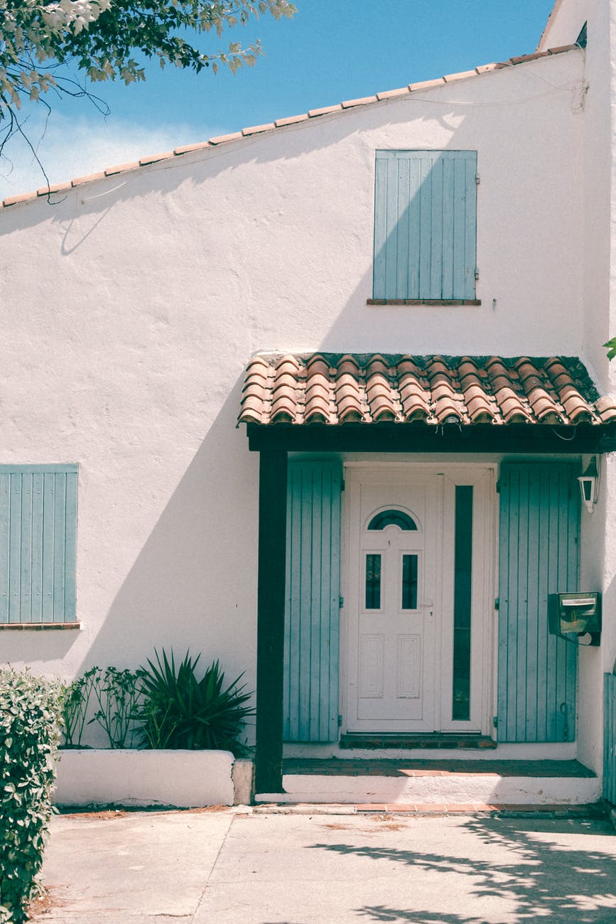 white stone house with blue shutters on sunny day