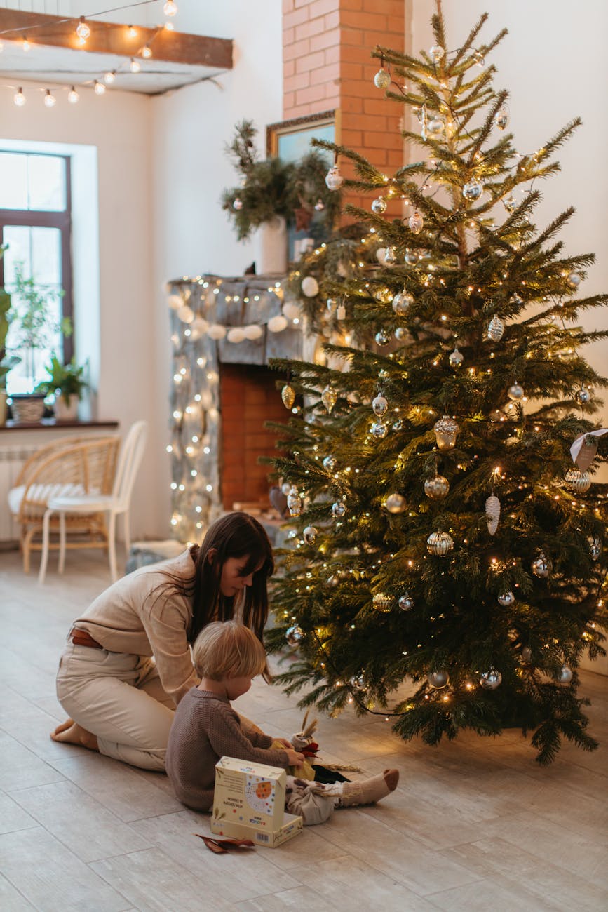a child sitting next to a christmas tree with his mom