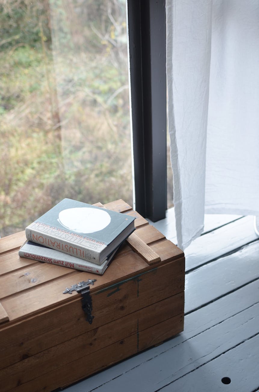 wooden chest with books on top near window