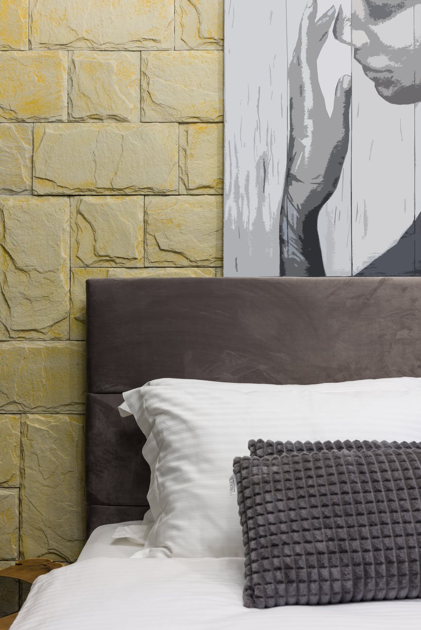 bed with decorative cushions under painting in house