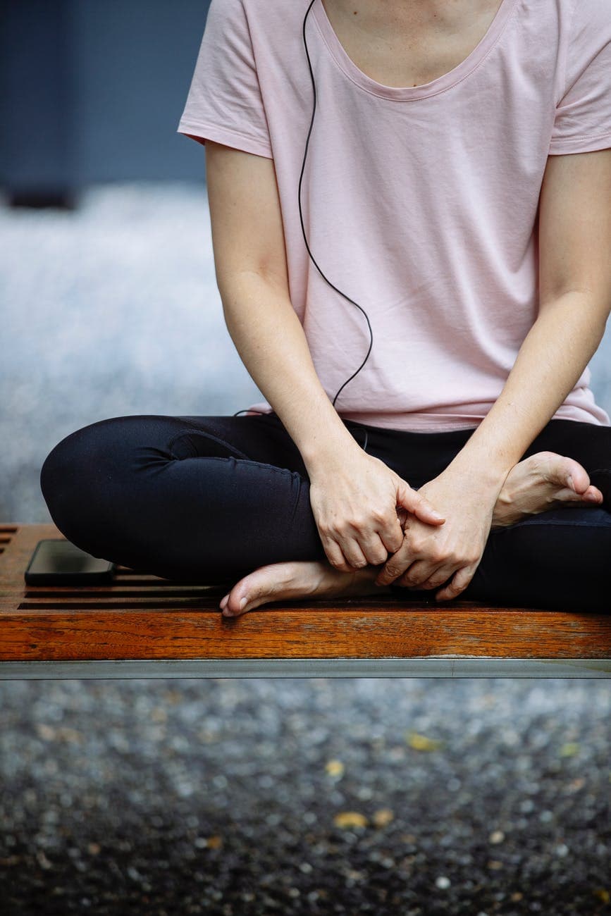 unrecognizable woman meditating in lotus pose on bench