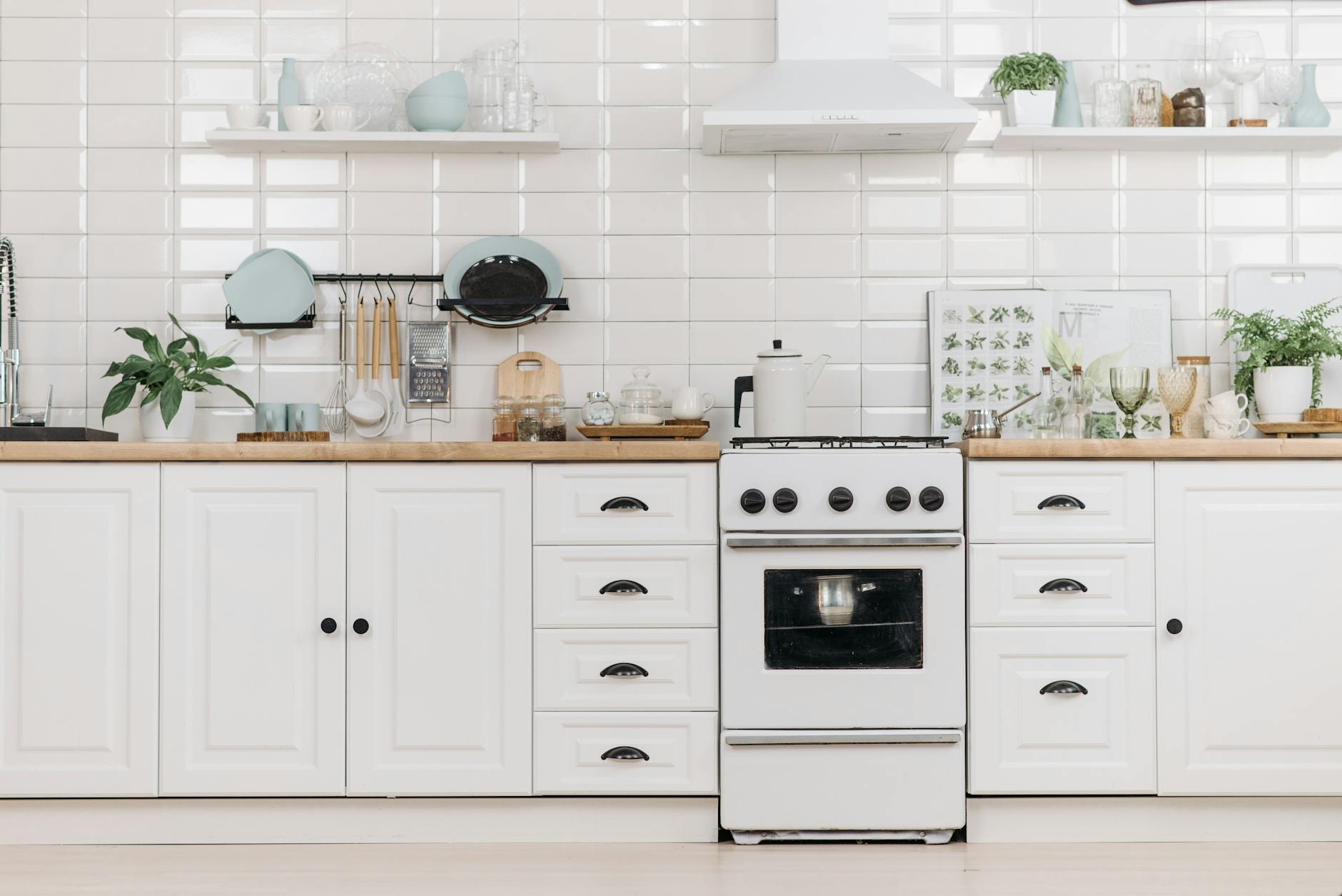 white wooden kitchen cabinets with dishware and stove