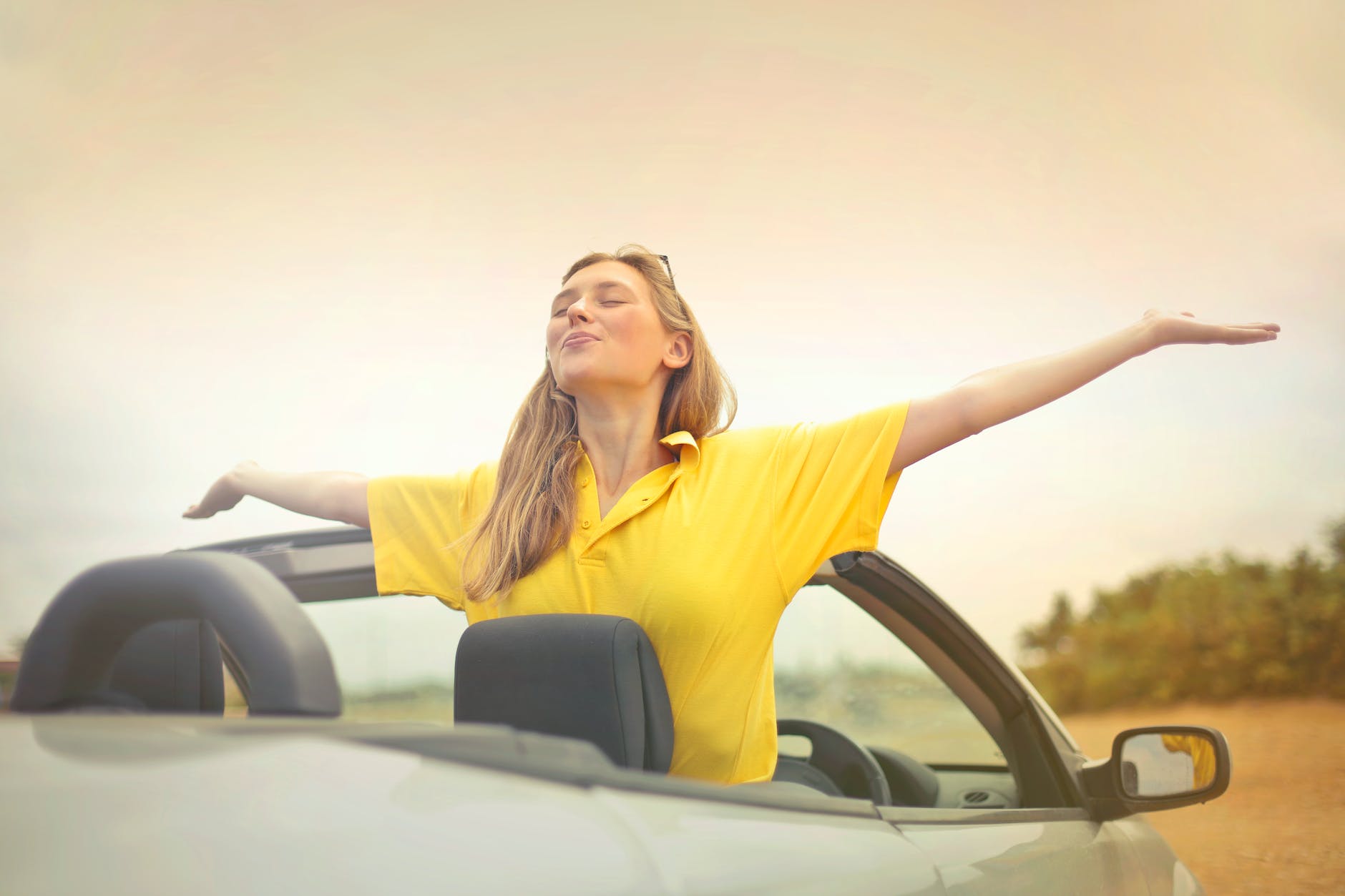 woman sitting on car under gray sky