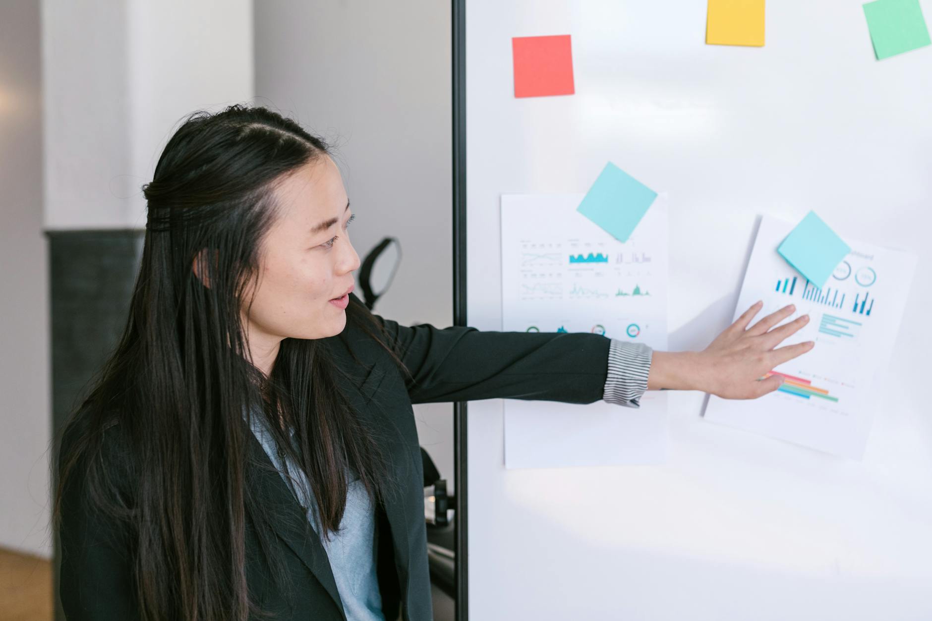 woman in black blazer standing beside white board