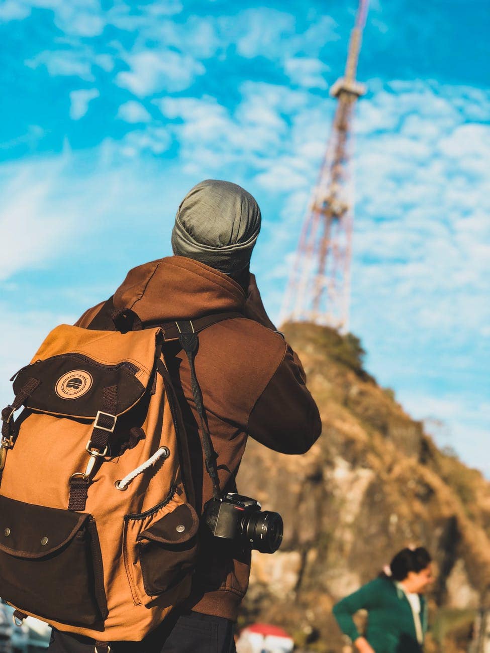 focus photography of person wearing brown and black jacket with brown and black backpack