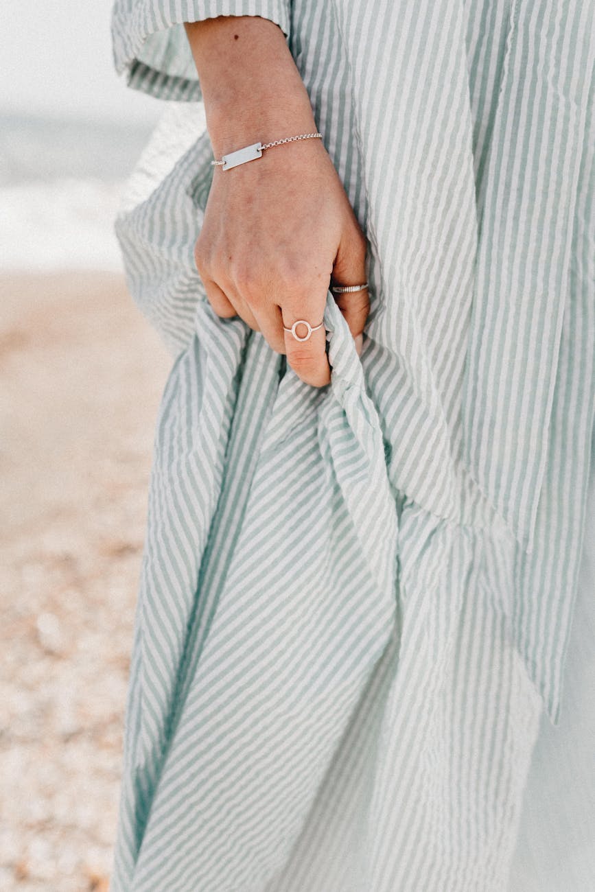 hand of woman holding light dress on background of seashore