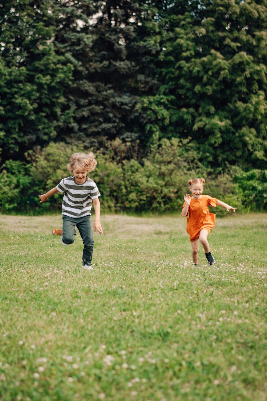 a boy and girl running on the grass together