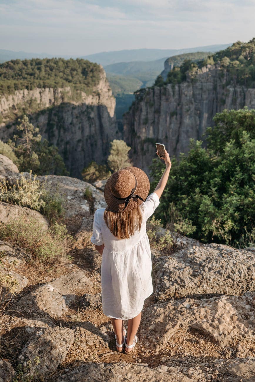 woman standing on a cliff taking selfie