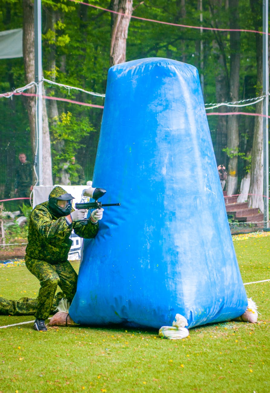 person in full protective gear using paintball gun